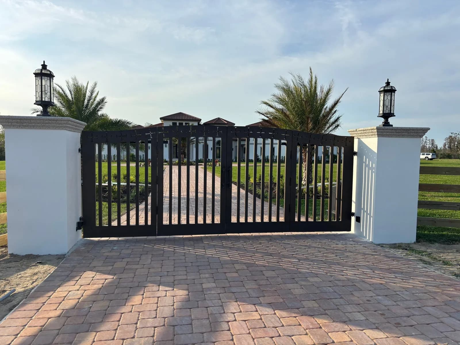 Black ornamental double swing gate between white pillars at an estate entrance in Clermont, FL