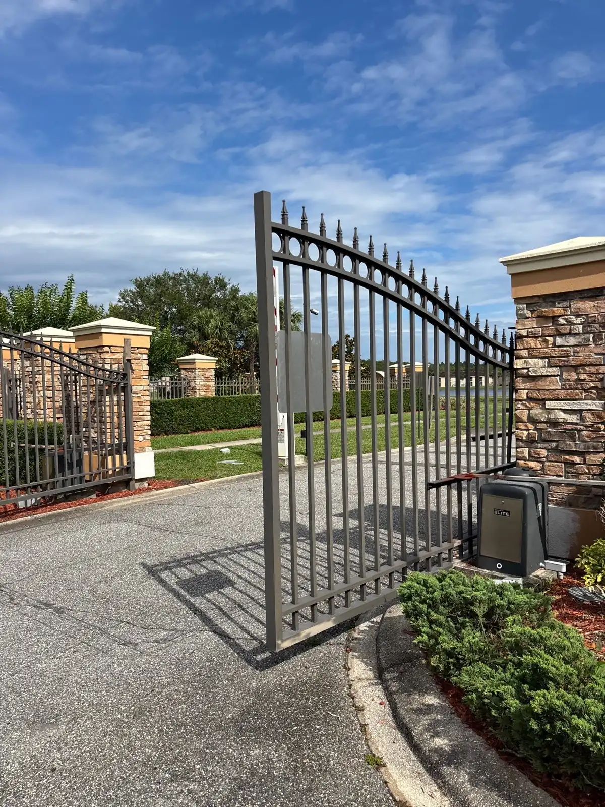Swing gate open between brick columns at a landscaped entry in Orlando, FL